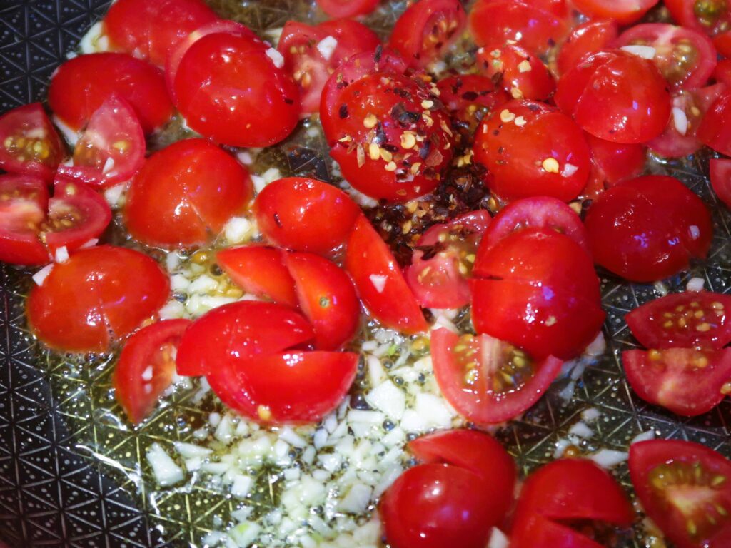 cooking the cherry tomatoes with the garlic and chilli